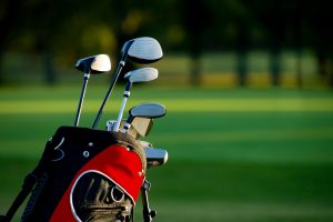 Golf clubs in a black and red bag with a golf course in the background