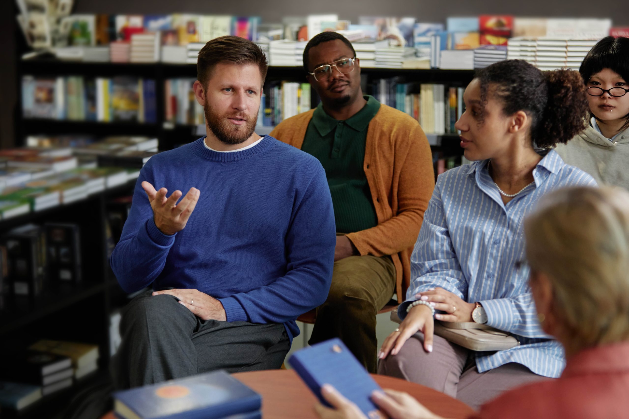 A group of adults sitting in a library discussing a book