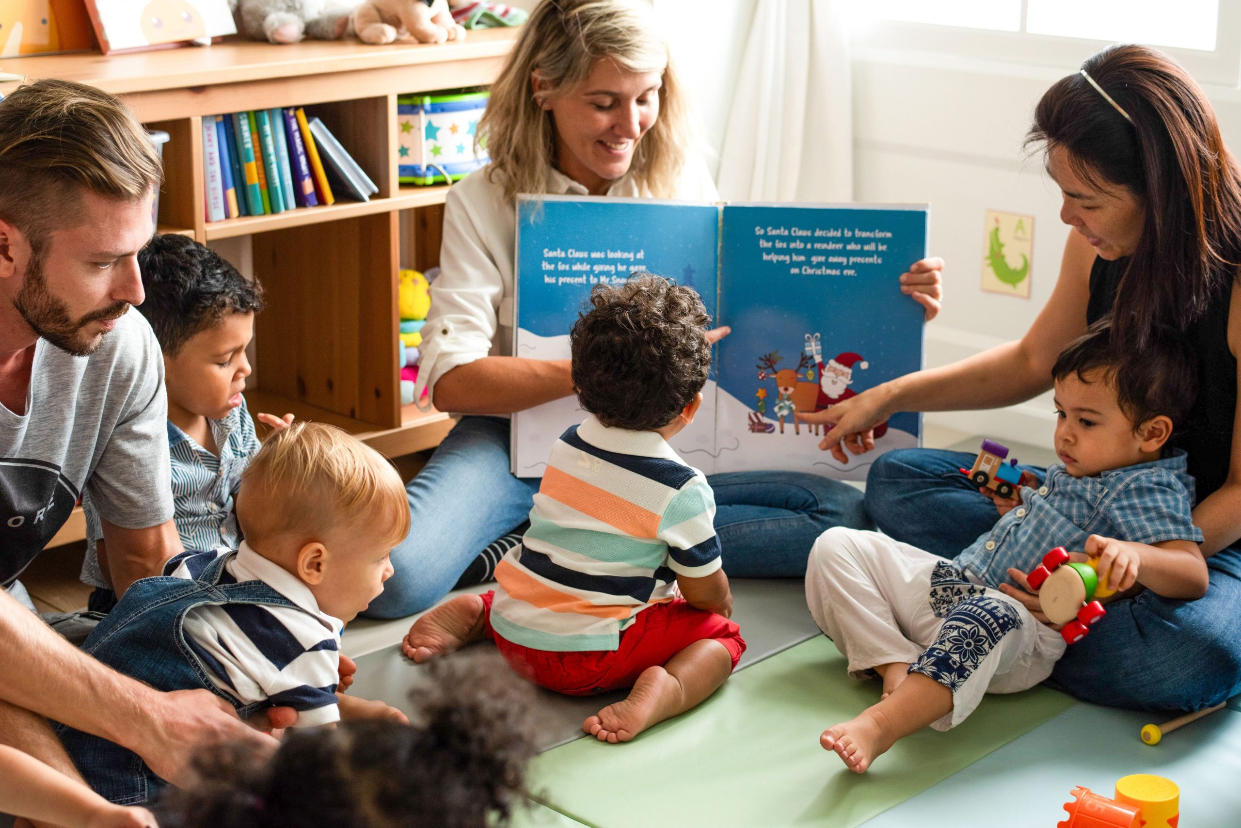 A woman showing a group of children and parents the inside of a book she's reading to them
