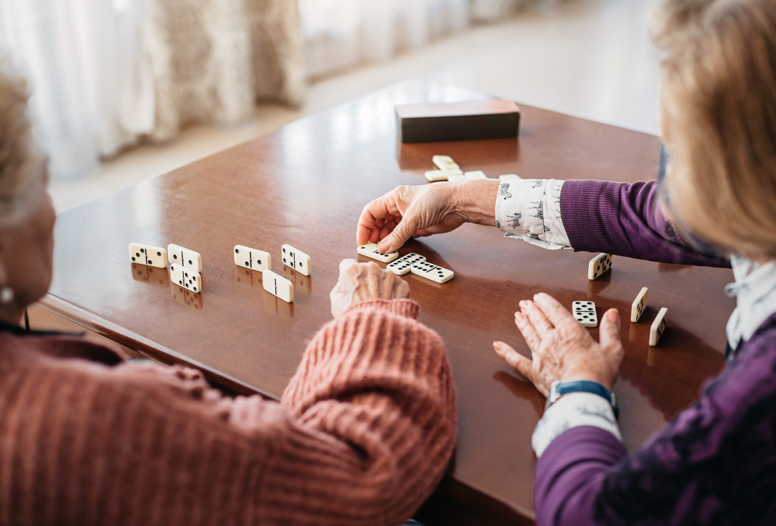 A pair of older women playing the game dominoes