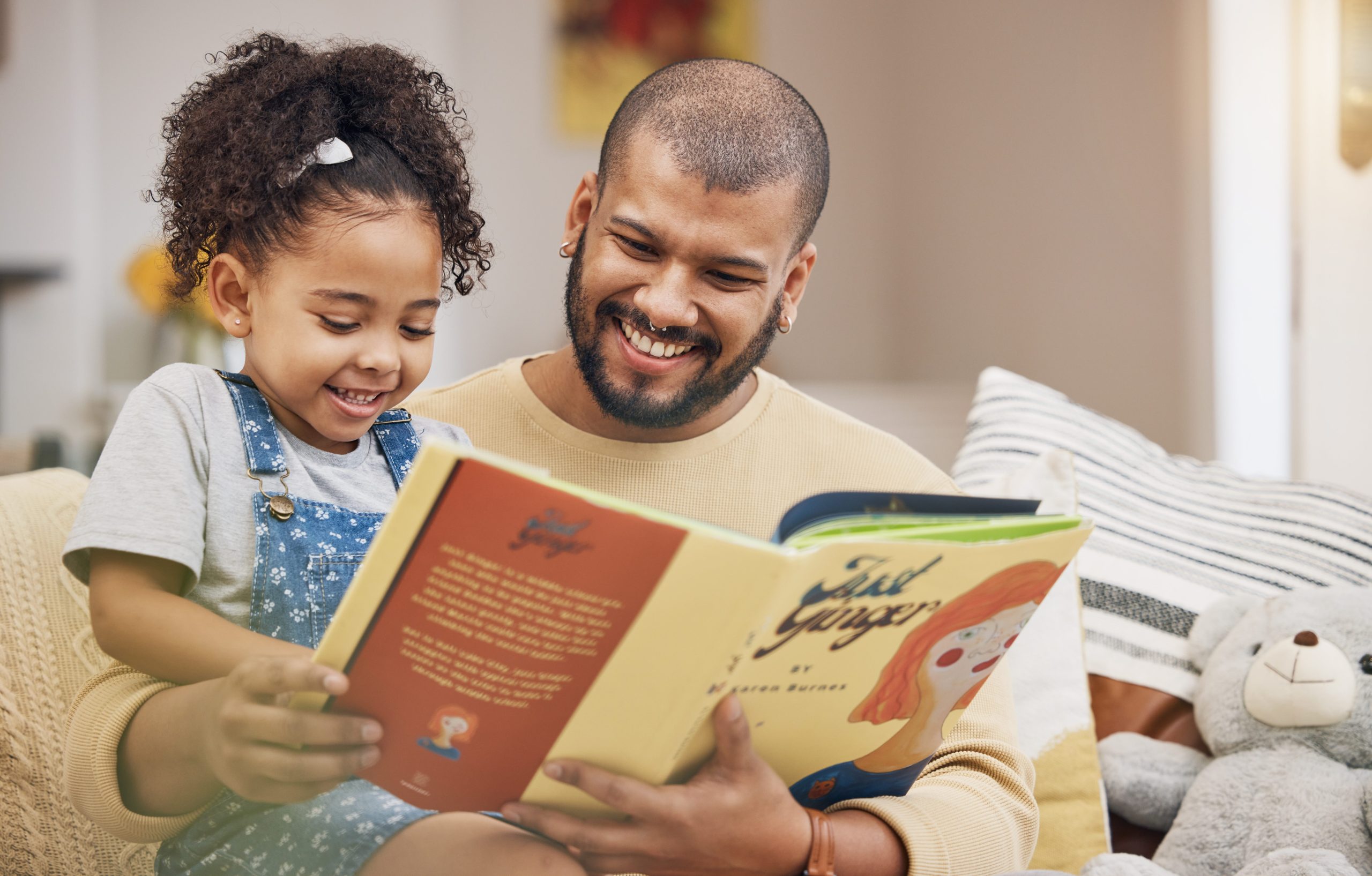 A smiling father reading a children's book to his daughter