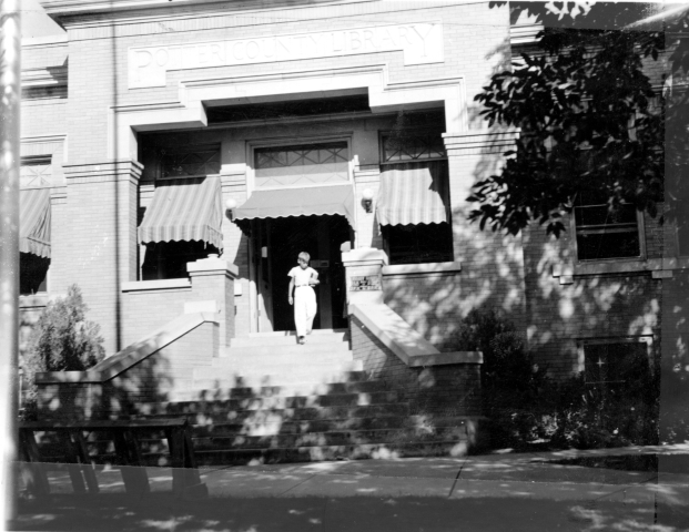 A vintage photo of a woman walking out of the previous Potter County Library