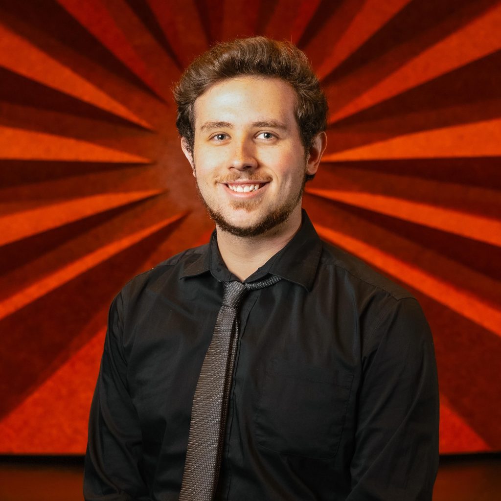 Headshot of Civic Center's Assistant Production Manager Kaleb Chamblee wearing a black long sleeve button down and silver tie