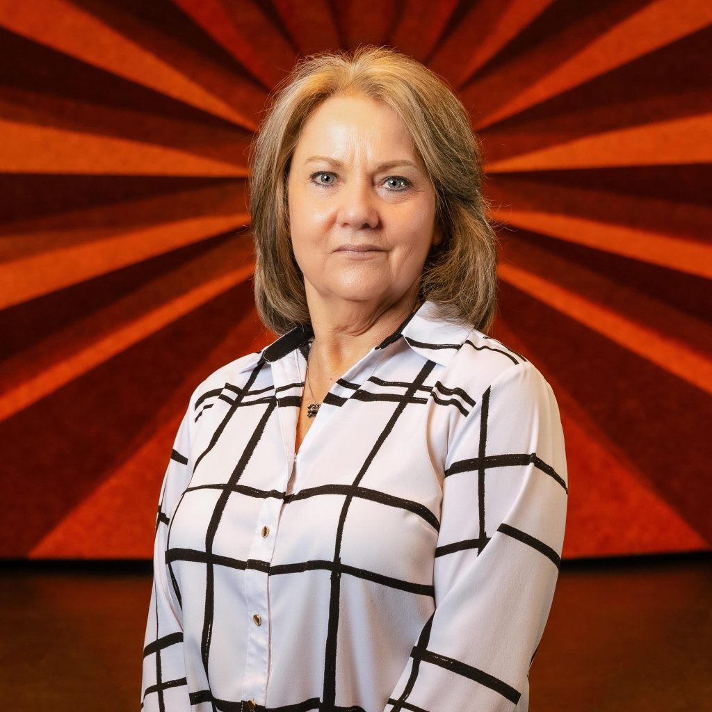 Headshot of Civic Center's Assistant Box Office Manager Mary Sawyer wearing a white long sleeve button down shirt that has black stripes on it