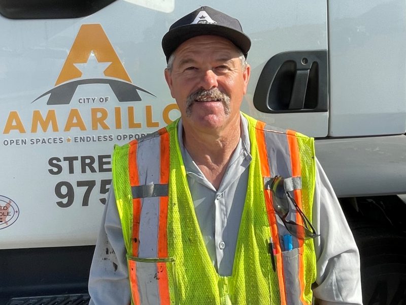 Paul Lundegreen, Street Department Utility Worker, in safety gear beside a city repair truck.