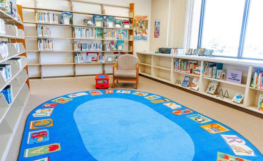 The audio area at the East Branch featuring a chair next to a large blue rug with the alphabet on it