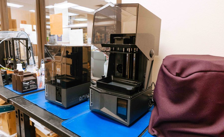 Multiple 3D printers, one with its lid open