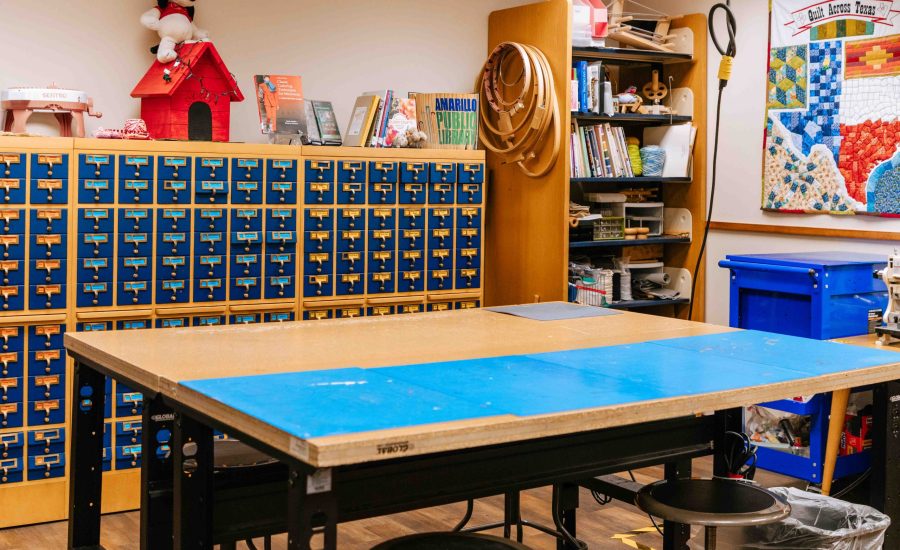 A large crafting table with a tiny parts organizer behind it