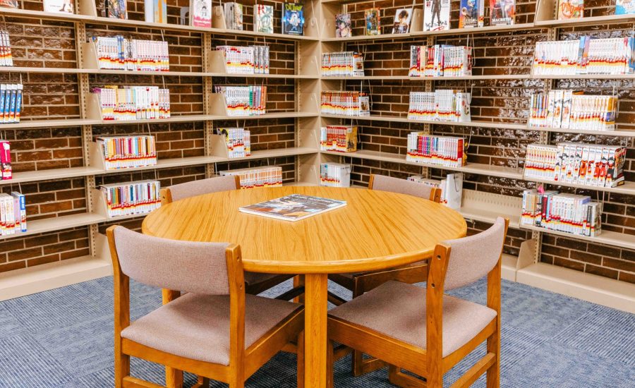 A circular table with chairs surrounding it in front bookshelves