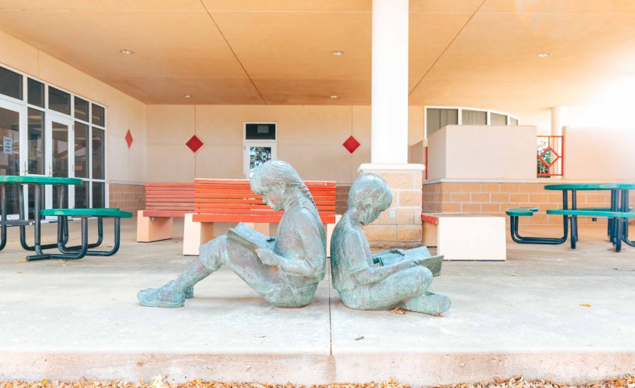 Another outdoor patio at the Southwest Branch featuring a bronze statue of two kids with their backs to each other, sitting on the ground, and reading books
